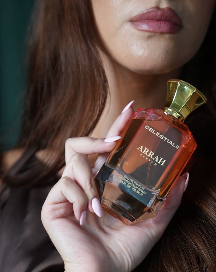 orange bottle of Arrah parfum our fragrance held by a woman 