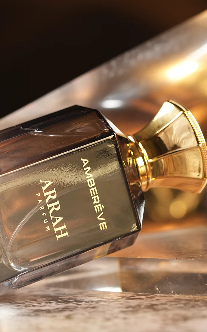 Perfume bottle with gold cap on a reflective surface